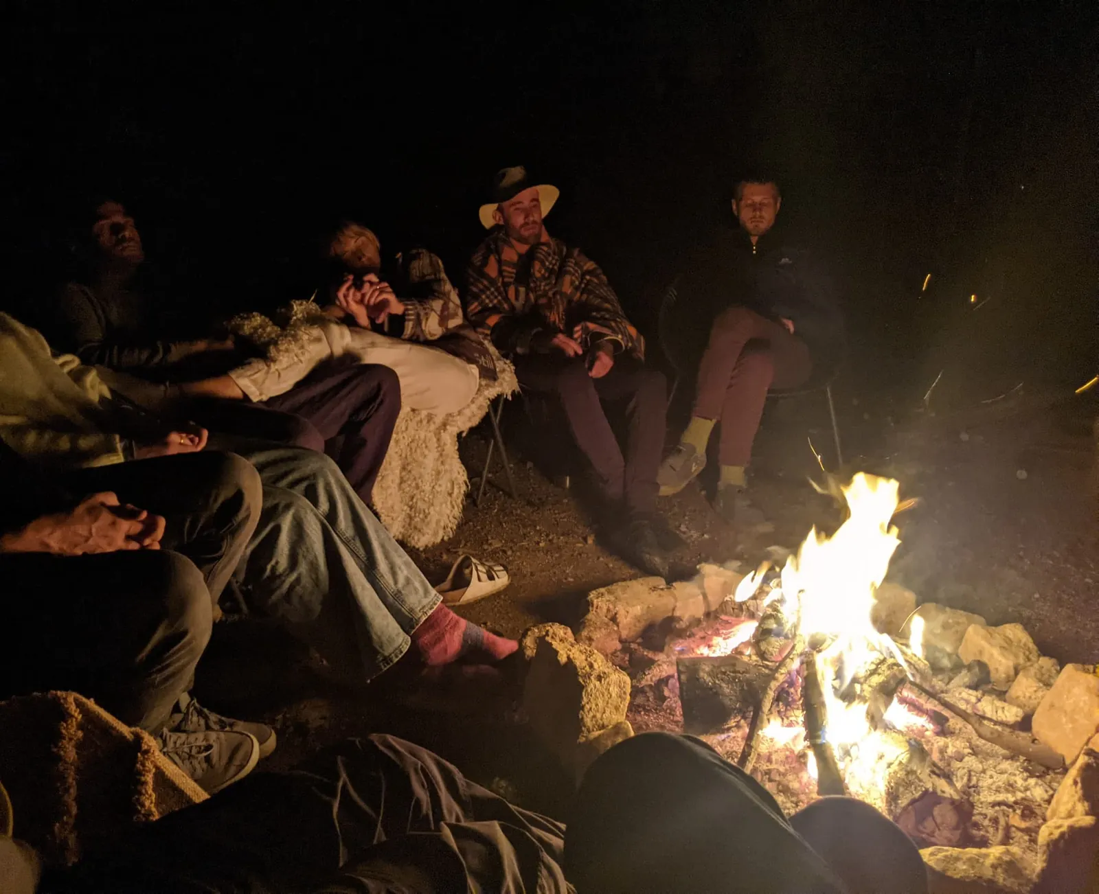 Brothers sitting together around a campfire at night